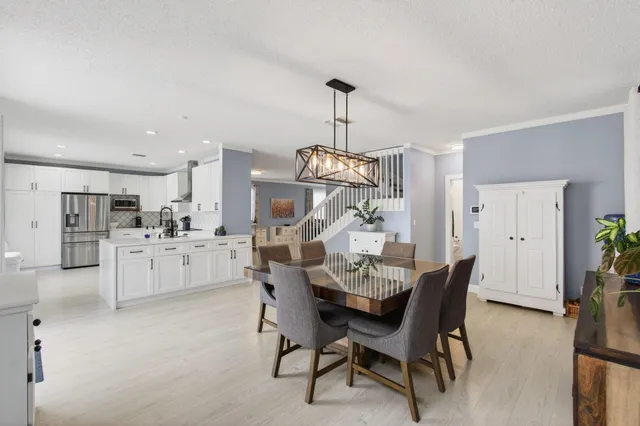 a view of a dining room and livingroom with furniture wooden floor a chandelier