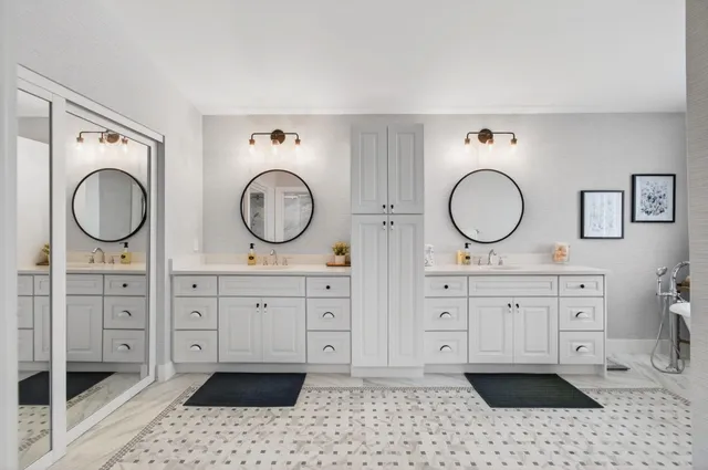 a white bath tub sitting next to a white sink and a mirror