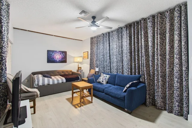 a view of a patio with table and chairs potted plants and floor to ceiling window