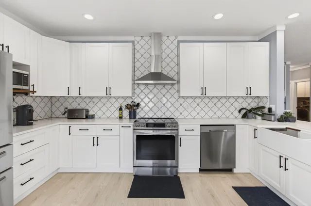 a kitchen with stainless steel appliances granite countertop a stove and white cabinets