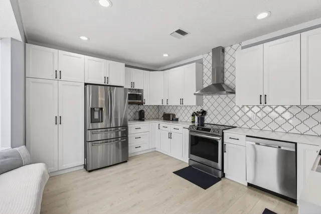a kitchen with stainless steel appliances granite countertop a refrigerator stove and white cabinets