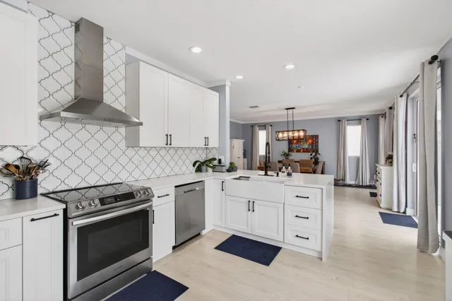 a kitchen with stainless steel appliances white cabinets and a stove top oven