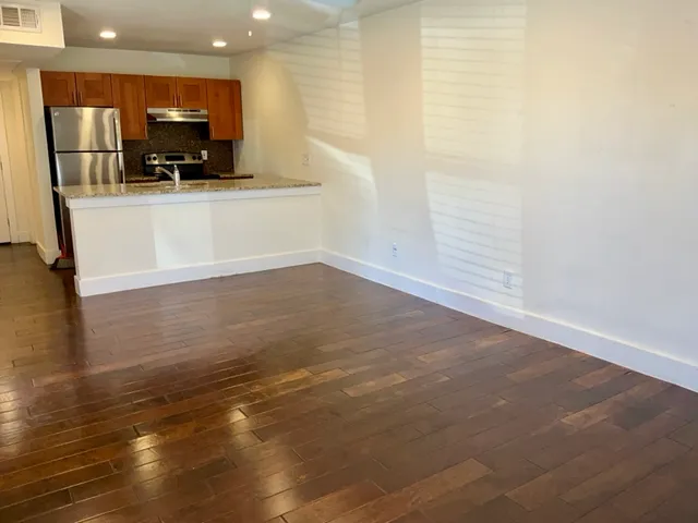 a view of kitchen with stainless steel appliances wooden floor and living room view