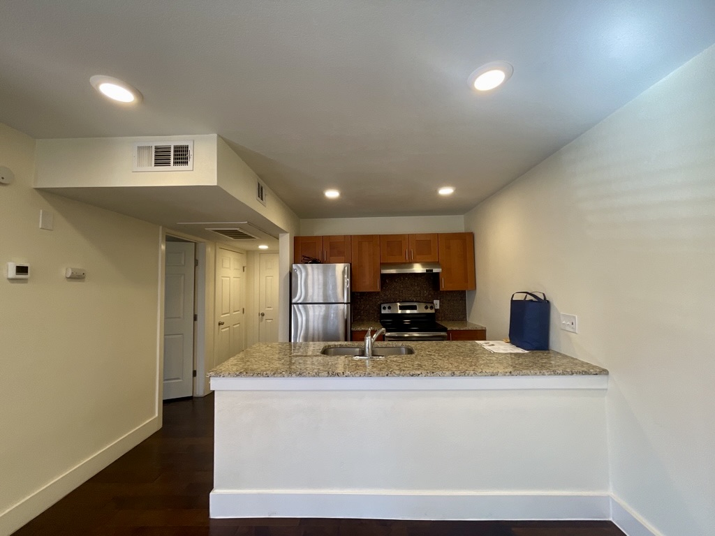 909 Reinli Street, Unit 124 Austin, TX 78751 - Photo 6 of 12 Kitchen with stainless steel appliances, brown cabinets, tasteful backsplash, a peninsula, and dark wood finished floors