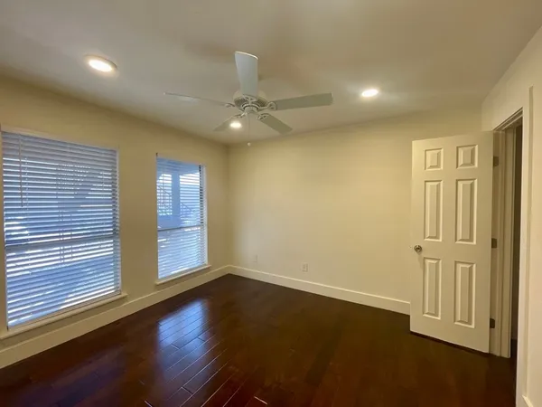 an empty room with wooden floor and a ceiling fan