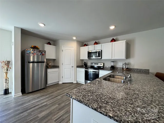 a kitchen with stainless steel appliances granite countertop a stove a sink and a microwave