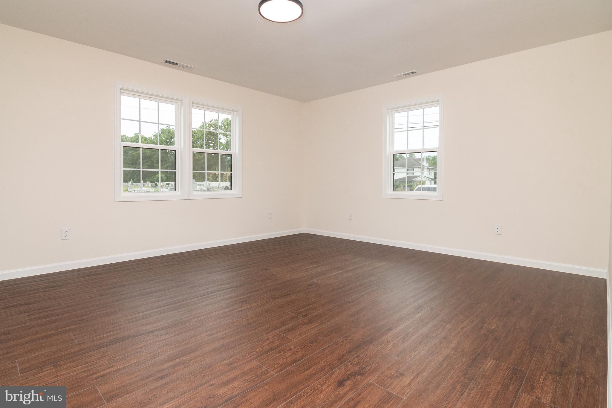 105 East Adams Street Georgetown, DE 19947 - Photo 17 of 49 an empty room with wooden floor and windows