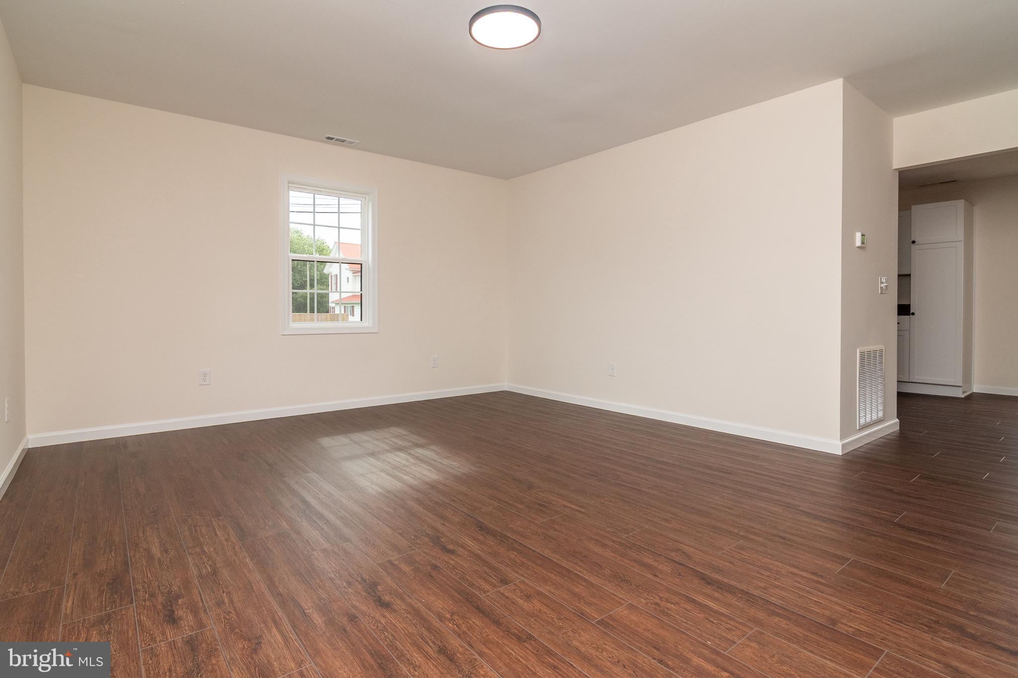 105 East Adams Street Georgetown, DE 19947 - Photo 20 of 49 an empty room with wooden floor and windows