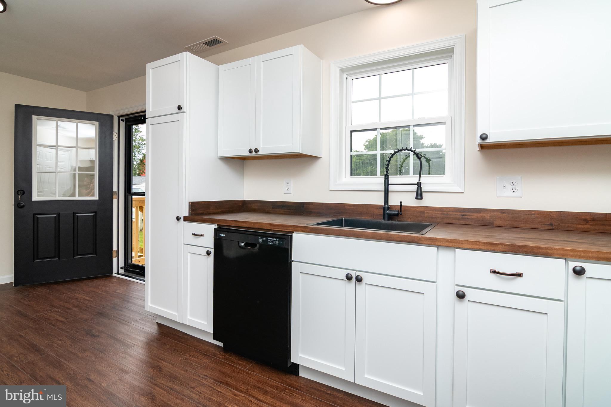 105 East Adams Street Georgetown, DE 19947 - Photo 41 of 49 a kitchen with granite countertop white cabinets and black appliances