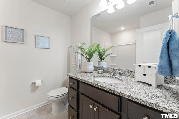 a bathroom with a granite countertop sink a mirror and a toilet