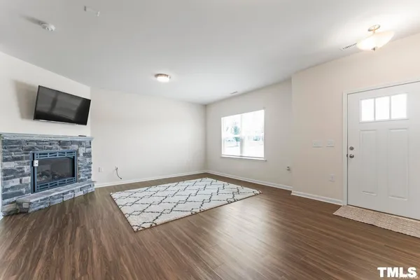 an empty room with windows a fireplace and wooden floor