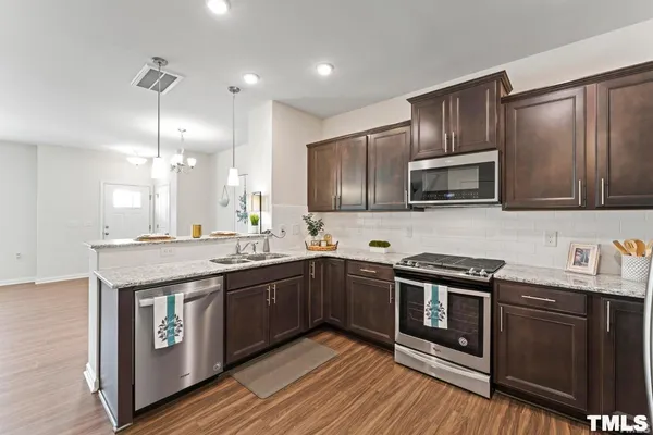 a kitchen with stainless steel appliances granite countertop a sink a stove and a wooden floors