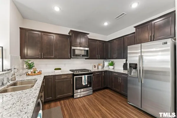 a kitchen with stainless steel appliances wooden cabinets a sink and a refrigerator