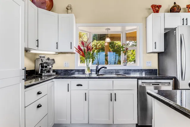 a kitchen with stainless steel appliances granite countertop a refrigerator a sink a stove a dining table and chairs with wooden floor