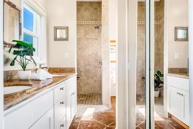 a bathroom with a granite countertop sink a mirror and shower