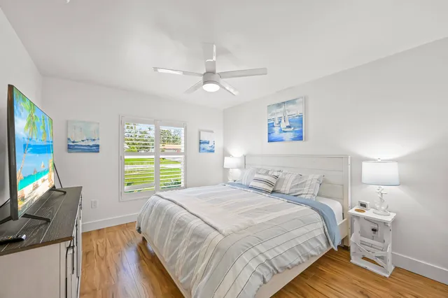 a bedroom with a bed a computer on the desk and a dresser next to a window