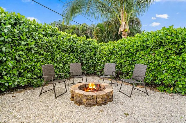 a backyard of a house with table and chairs under an umbrella