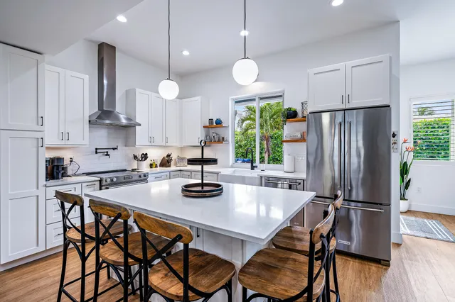 a kitchen with stainless steel appliances granite countertop a stove a refrigerator a kitchen island a table and chairs