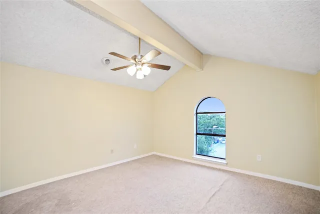 an empty room with a chandelier fan and windows