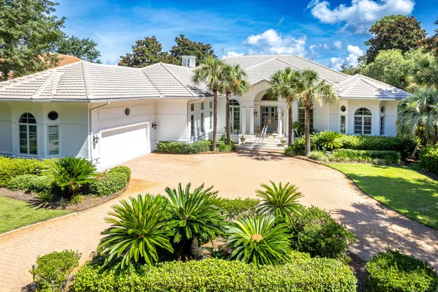 a view of a white house with a big yard and potted plants