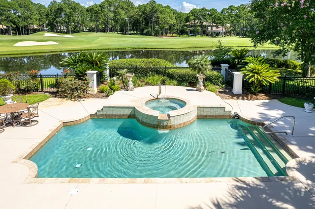a view of a swimming pool and lounge chairs in back yard of the house