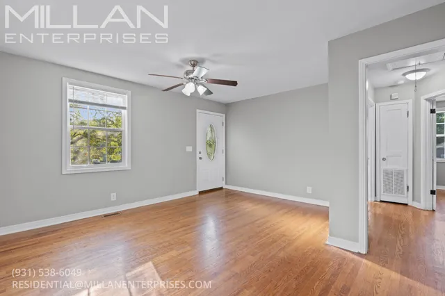 a view of an empty room with wooden floor and a window
