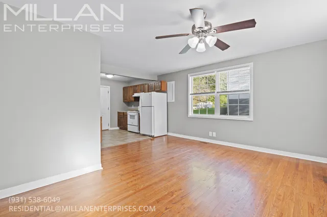 an empty room with wooden floor chandelier fan and windows