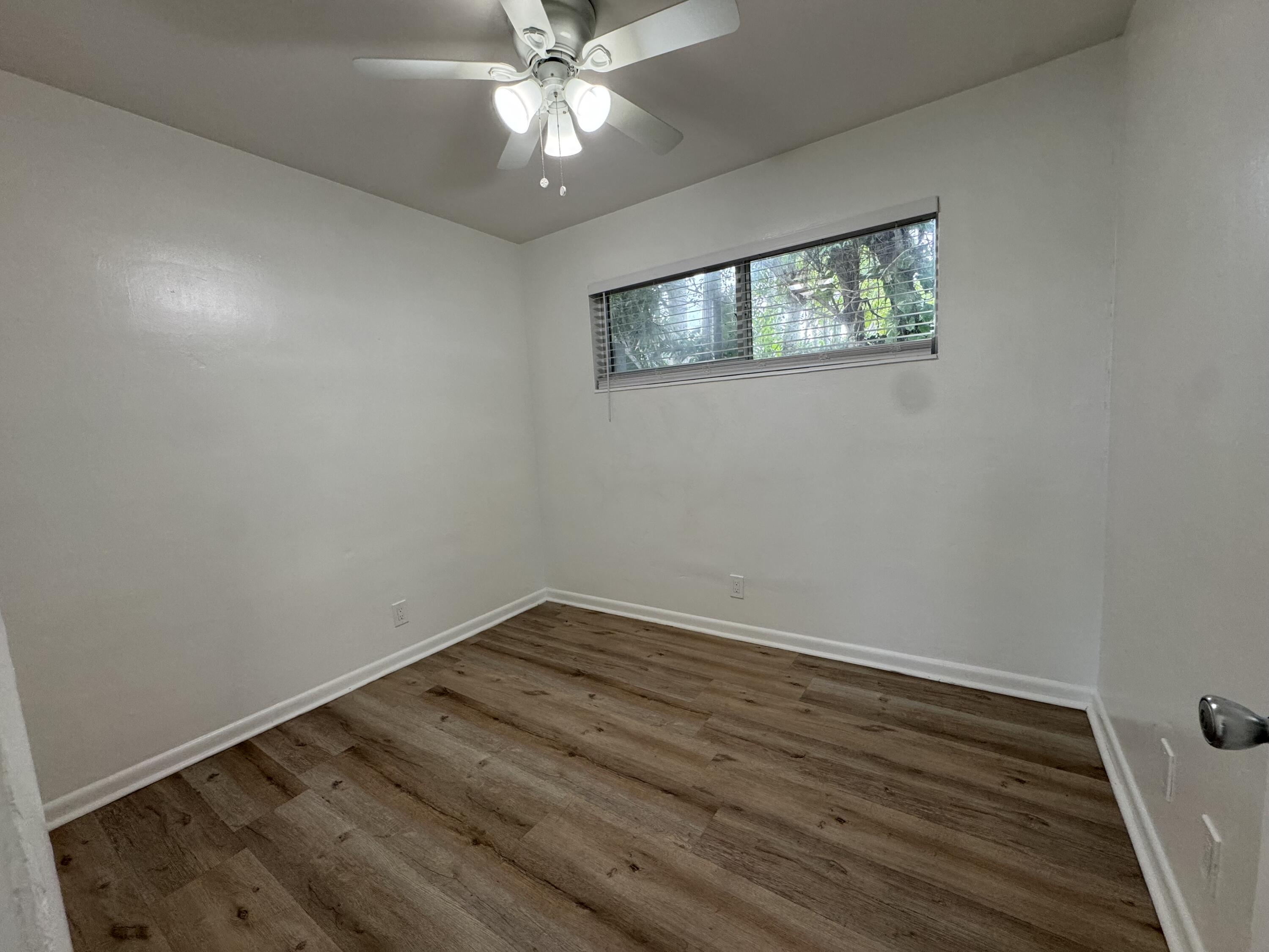 1235 Beach Road, Unit 4 Singer Island, FL 33404 - Photo 12 of 13 a view of an empty room with wooden floor and a window
