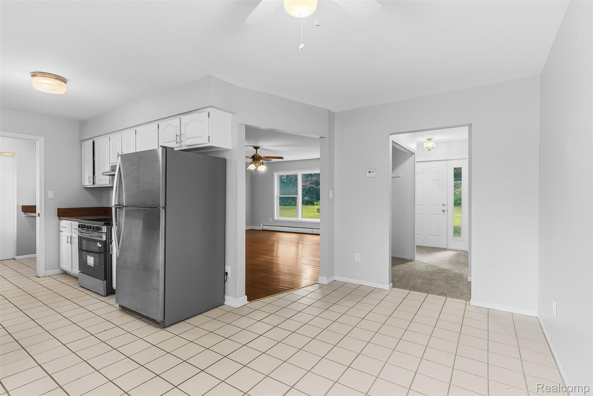 9200 Hickory Ridge Road Holly, MI 48442 - Photo 13 of 33 Kitchen featuring tile flooring, stainless steel refrigerator, white cabinetry, dark countertops, and a range oven
