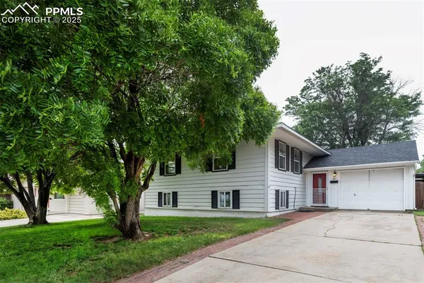 a front view of a house with a garden and trees