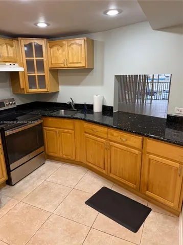 a view of kitchen with stainless steel appliances wooden cabinet and refrigerator