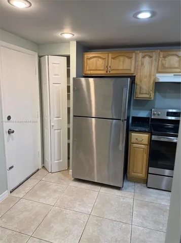 a kitchen with granite countertop a refrigerator a sink and wooden cabinets