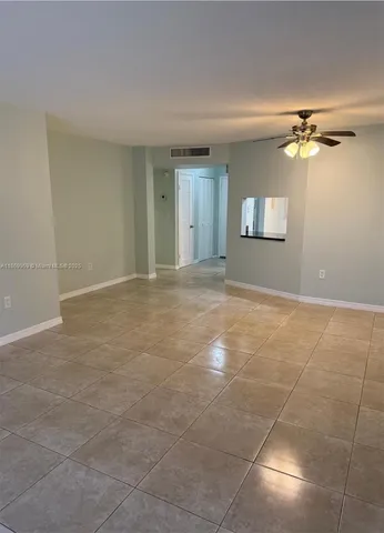 a view of an empty room and chandelier fan