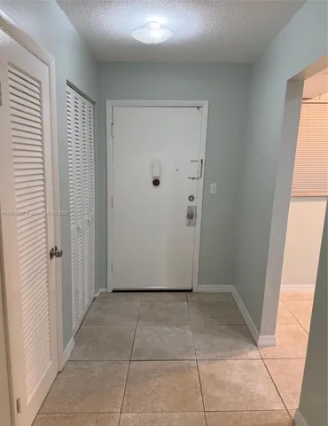 a view of a refrigerator in kitchen and an empty room