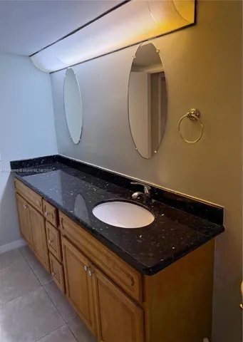 a bathroom with a granite countertop sink and a mirror