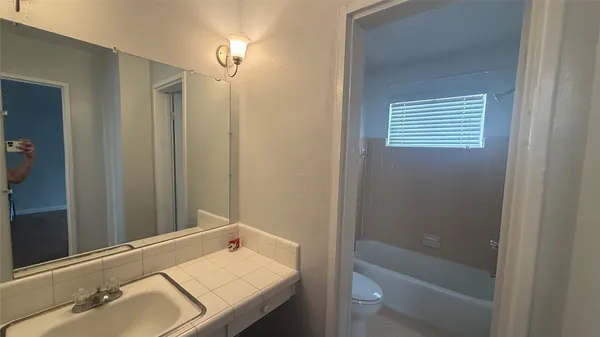 a bathroom with a tub sink vanity and a mirror
