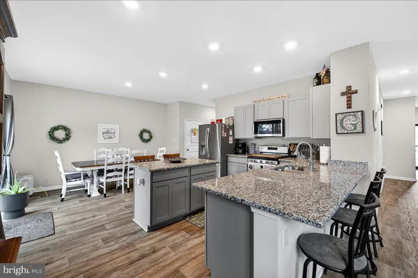 a kitchen with stainless steel appliances granite countertop a stove top oven a sink dishwasher a dining table and chairs with wooden floor