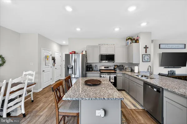 a kitchen with stainless steel appliances granite countertop a stove top oven a sink dishwasher a dining table and chairs with wooden floor