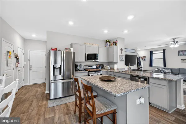 a kitchen with stainless steel appliances granite countertop a stove top oven a refrigerator a sink and a stove with wooden floor