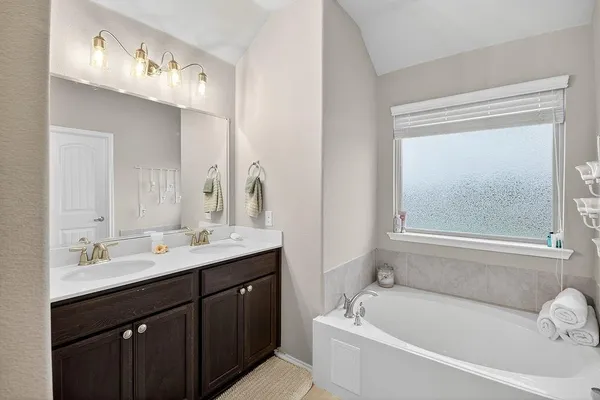 a bathroom with a tub a sink and mirror
