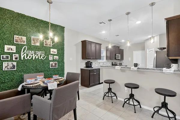 a kitchen with a dining table chairs refrigerator and sink
