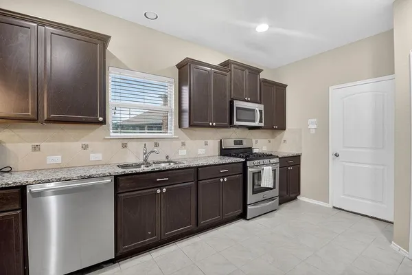 a kitchen with stainless steel appliances granite countertop wooden cabinets a stove a sink and a microwave