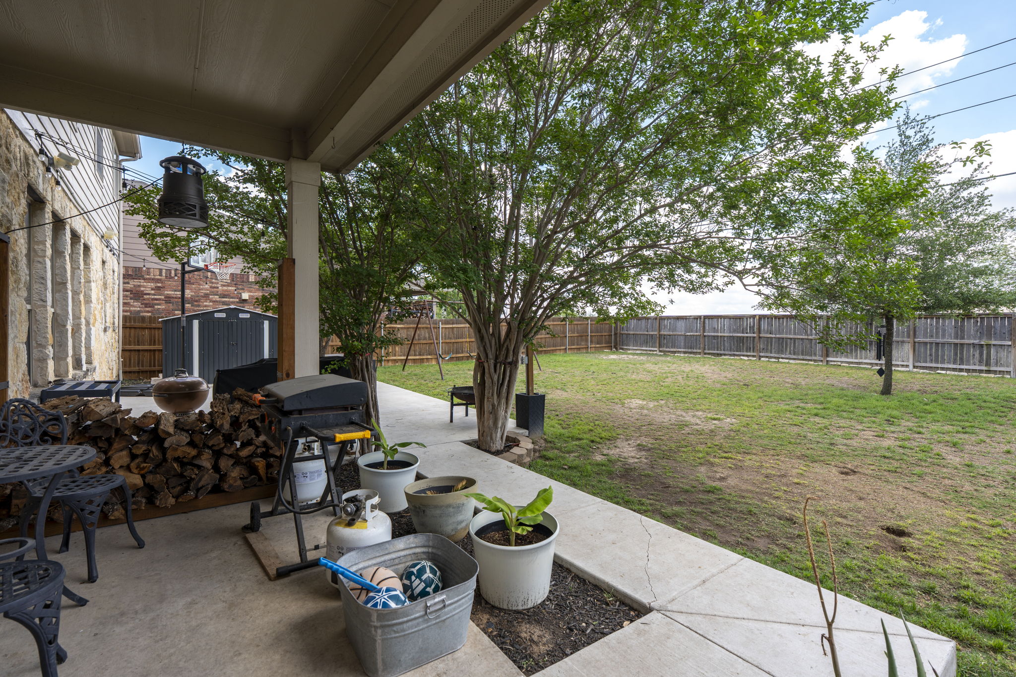 227 Sandstone Trail Buda, TX 78610 - Photo 22 of 33 Expansive rear patio with concrete flooring, covered porch, wood-look siding, and stone exterior accents