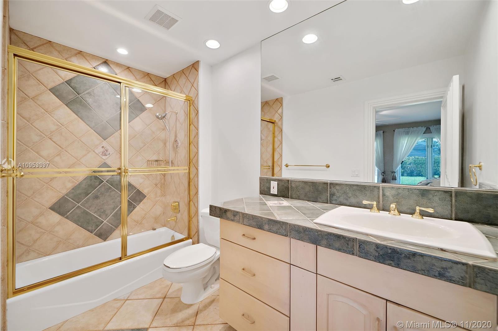 9100 Southwest 103rd Street Miami, FL 33176 - Photo 31 of 47 a bathroom with a granite countertop sink a toilet a mirror and shower