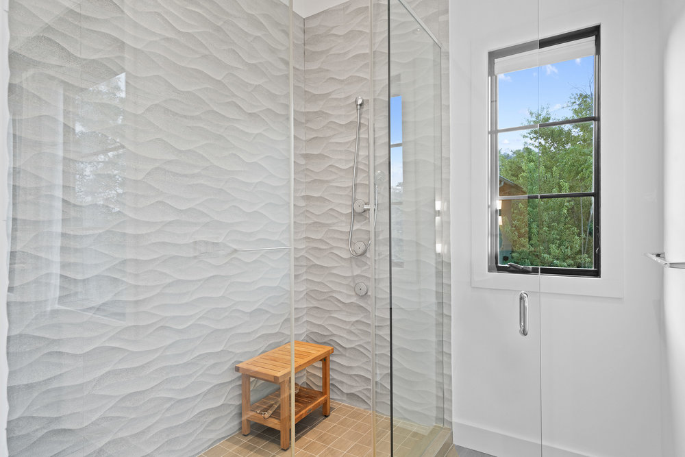 1905 Paisano Road Austin, TX 78746 - Photo 28 of 40 A glass-enclosed shower boasts captivating textured tile work and abundant natural light.