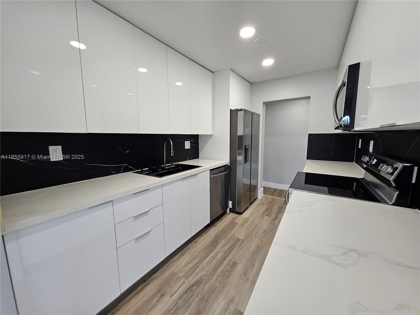 2865 Northeast 13th Avenue Pompano Beach, FL 33064 - Photo 4 of 19 a large white kitchen with stainless steel appliances a large counter top a stove a sink a refrigerator and a cabinets