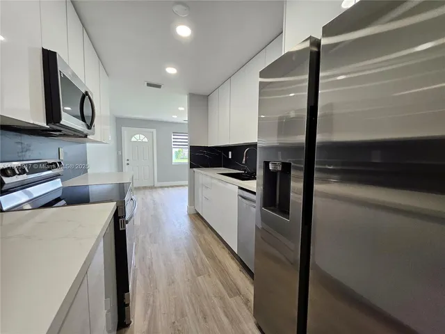 a kitchen with stainless steel appliances a refrigerator a stove top oven a sink and dishwasher