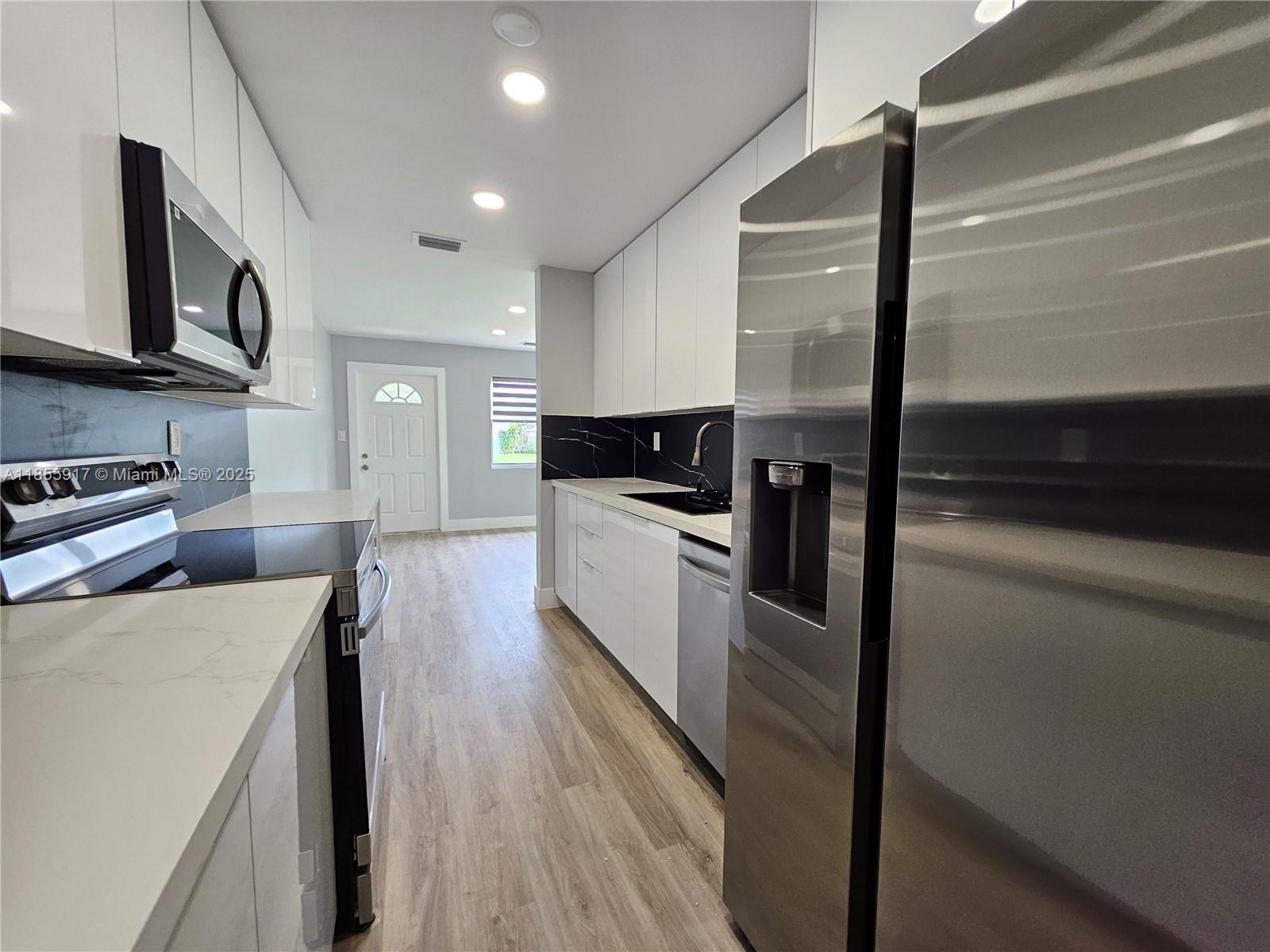2865 Northeast 13th Avenue Pompano Beach, FL 33064 - Photo 6 of 19 a kitchen with stainless steel appliances a refrigerator a stove top oven a sink and dishwasher