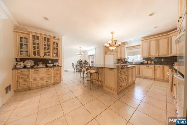 a kitchen with stainless steel appliances kitchen island granite countertop a stove a sink and white cabinets