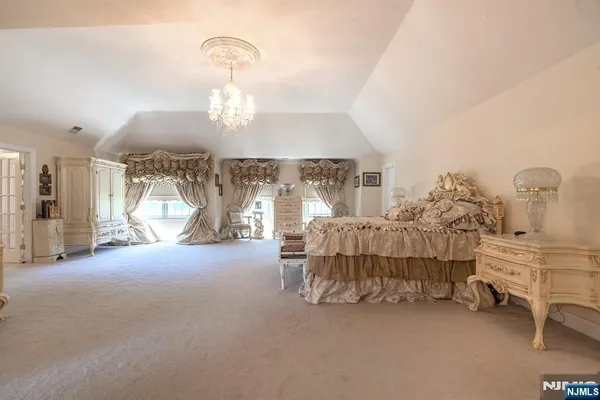 a room with lots of white furniture and a chandelier